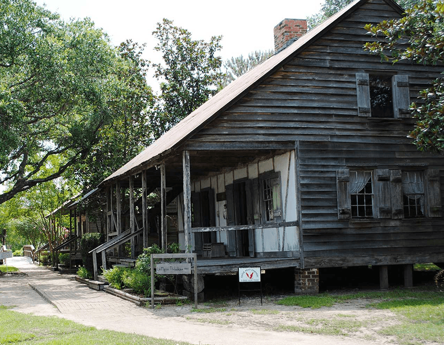 Historic wooden house surrounded by greenery.