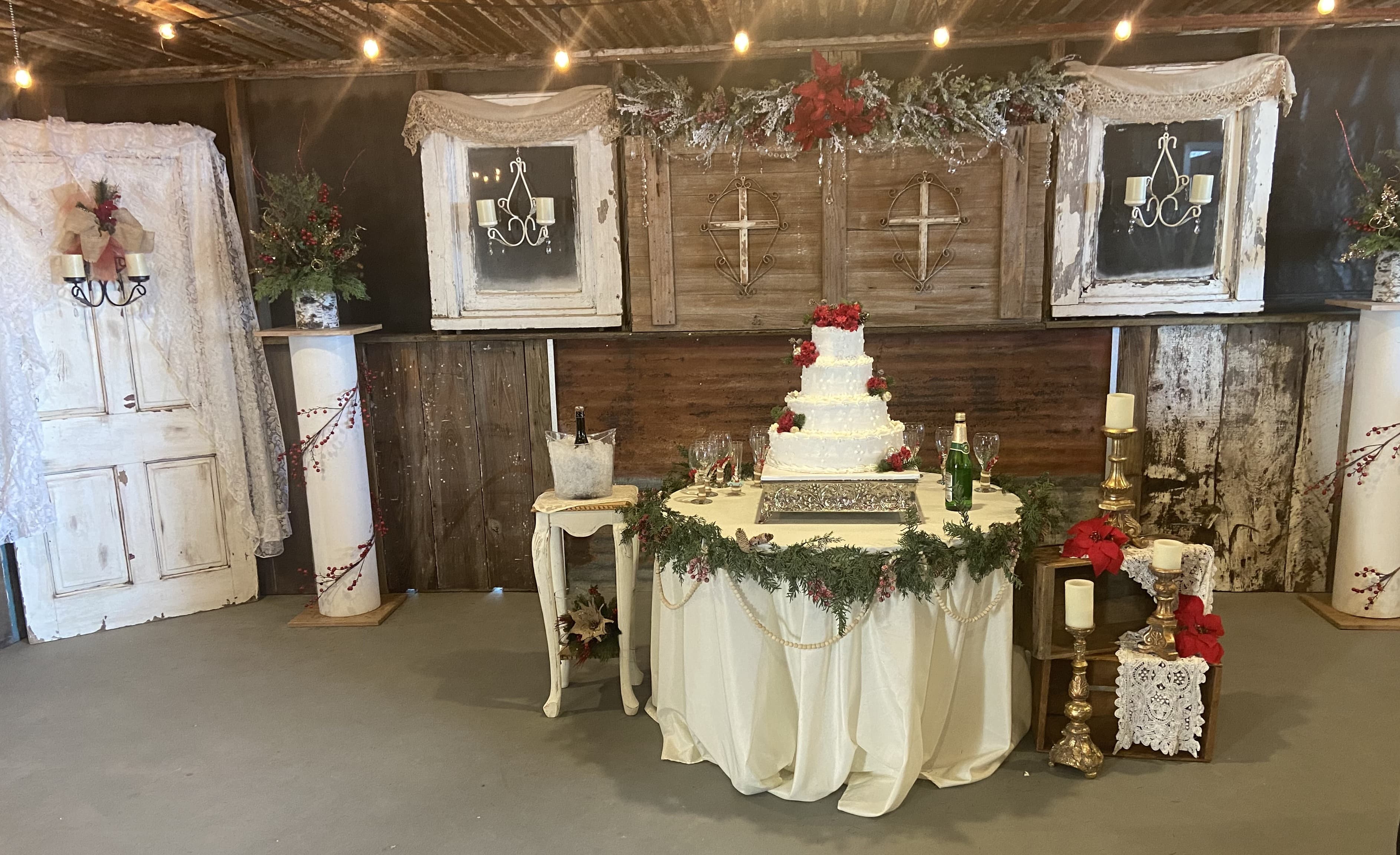 A beautifully decorated table with a multi-tiered wedding cake adorned with flowers, set in a rustic venue.