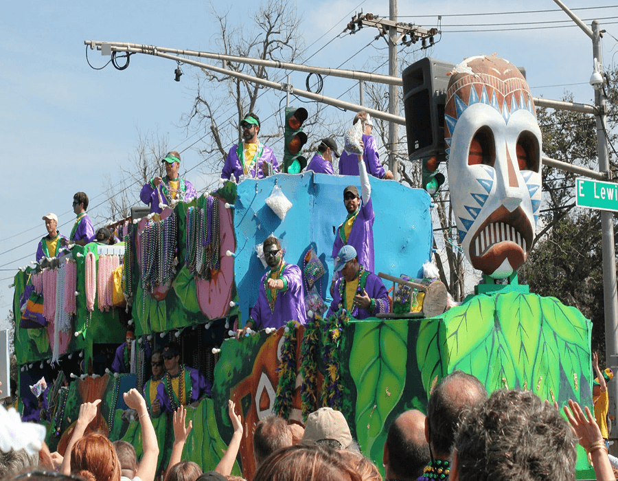 A colorful parade float features beaded decorations and participants in costumes celebrating Mardi Gras.