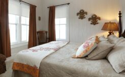 Fleur de Lis Room with brown curtains, beige bedspread, fleur de lis placks on wall