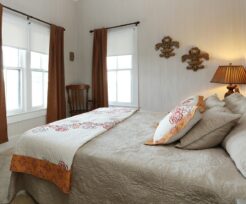 Fleur de Lis Room with brown curtains, beige bedspread, fleur de lis placks on wall