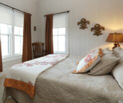 Fleur de Lis Room with brown curtains, beige bedspread, fleur de lis placks on wall